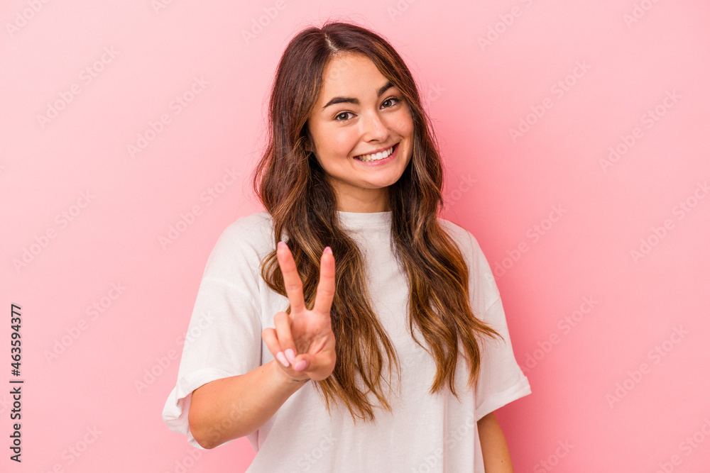 Fototapeta premium Young caucasian woman isolated on pink background showing victory sign and smiling broadly.