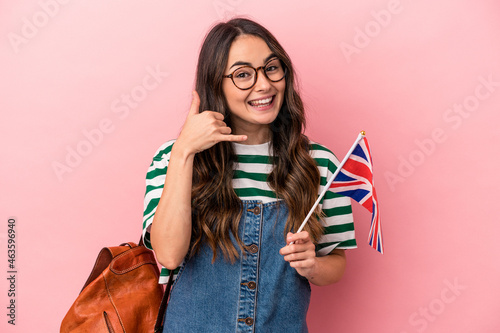 Young caucasian student woman studying English isolated on pink background showing a mobile phone call gesture with fingers.