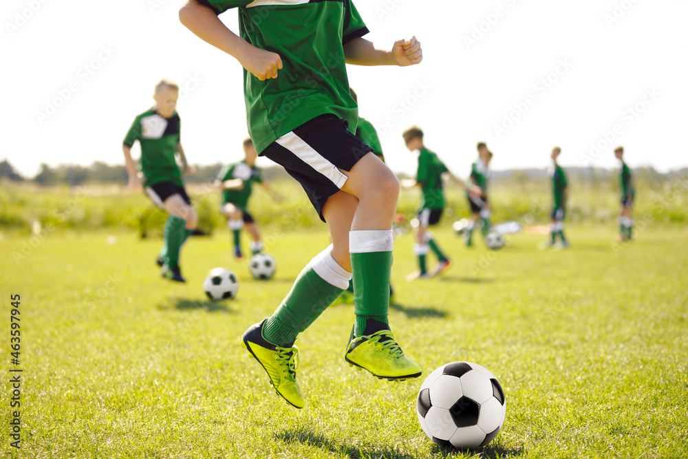 Boy on Grass Soccer Field Running Fast, Jumping and Kicking Ball. Football Team on Training Unit. Youth Football Team on Training Summer Camp