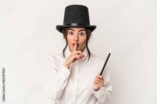 Foto Young magician woman holding a wand isolated on white background keeping a secret or asking for silence