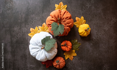 White, orange, yellow pumpkins and autumn leaves on an black background