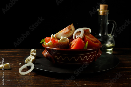Homemade salad of tomatoes, feta cheese and onions, with olive oil. In a ceramic bowl, low key, horizontal.
