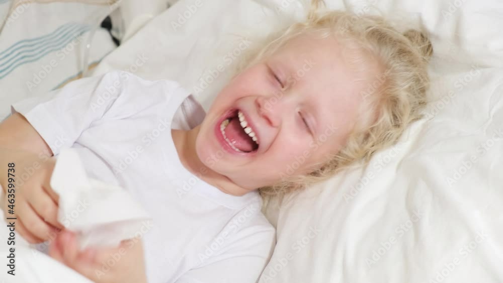 a cute little girl with curly blond hair lies in bed, a sick five-ribbon girl in bed blows her nose in a napkin 4k, girl laughing a cute little girl with curly blond hair lies in bed, a sick five-ribbon girl in bed blows her nose in a napkin 4k, girl laughing