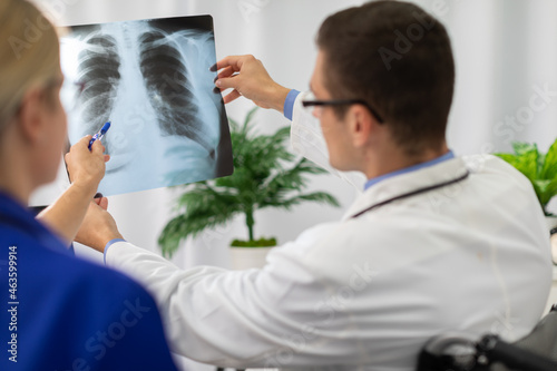 A doctor and nurse look at a photograph of a patient's lungs. © fotodrobik
