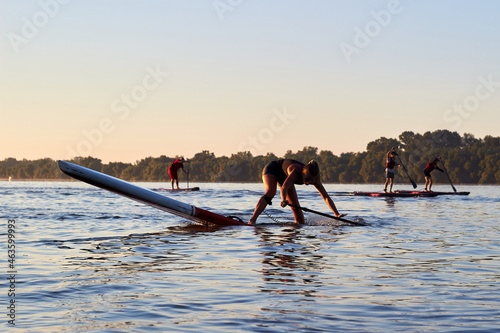 Silhouette of people training on Stand Up Paddle Board, SUP at summer morning at the river