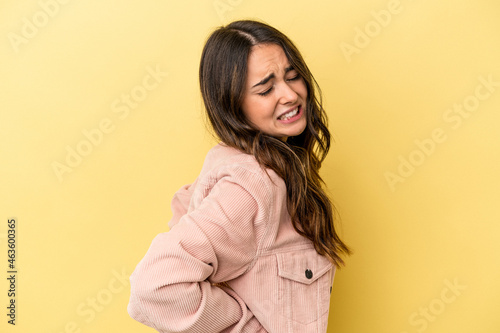 Young caucasian woman isolated on yellow background suffering a back pain.