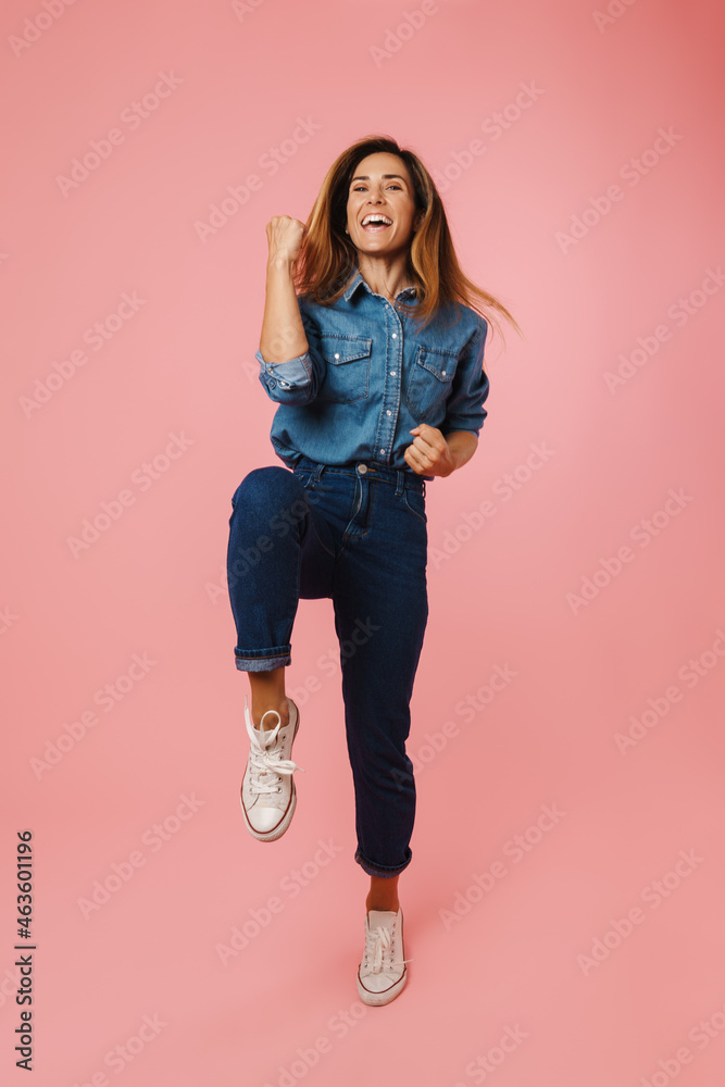 European ginger woman in jeans smiling and making winner gesture European ginger woman in jeans smiling and making winner gesture