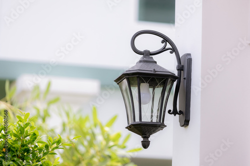 lamp light on the wall. Vintage iron lantern on the wall outdoor. Garden metal electrical lamp in a village. Wall lamp outdoor.