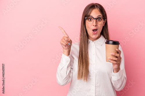 Young business caucasian woman holding a take away isolated on pink background pointing to the side