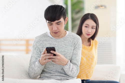 Young man using smartphone.Young woman peeks at man's smartphone screen.