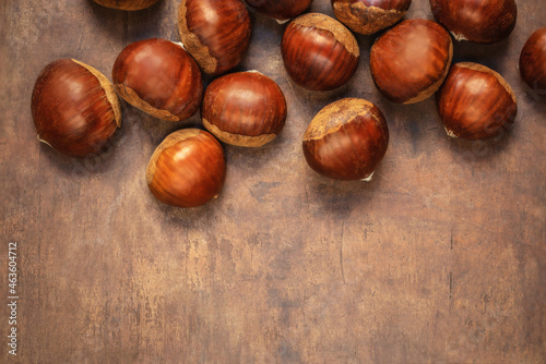 Sweet chestnuts on old rustic wooden table with plenty of copy space. Autumn fall concept. Horse chestnuts top view.