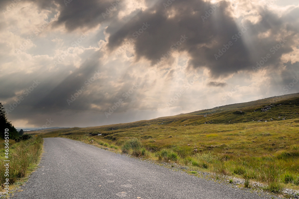 Small narrow country road in Connemara, county Galway, Ireland. Dramatic sky. Irish landscape. Beautiful nature scene