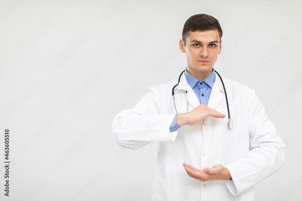 The doctor stands forward with a subdued expression and his hands raised.