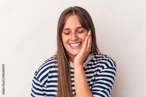 Young caucasian woman isolated on white background laughs happily and has fun keeping hands on stomach. © Asier