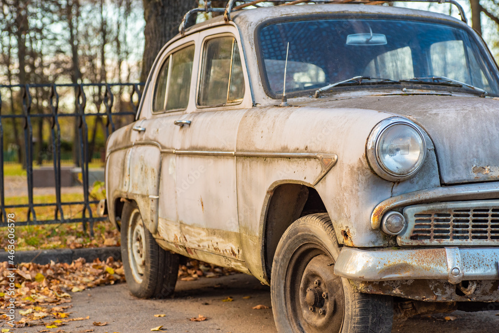 Vintage car with faded paint and traces of rust, blurred background
