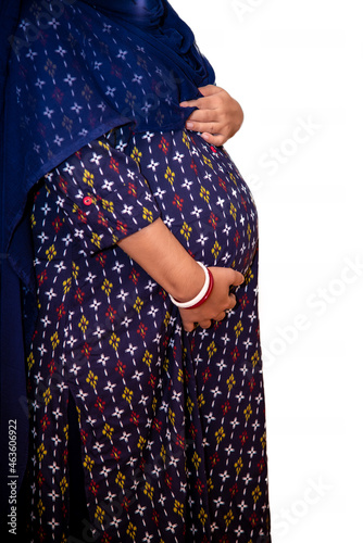 An 8-month-pregnant Indian woman on a white background is holding her belly. Pregnancy, maternity, preparation and expectation concept.