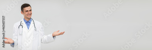 A smiling doctor spreads his arms out to the sides and leaves the choice to the patient. Panoramic view. © fotodrobik