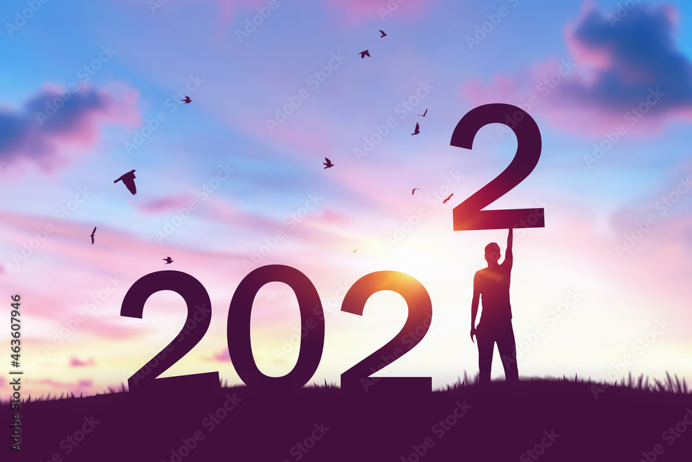 Man raise hand up on sunset sky with birds flying at top of mountain and number like 2022 abstract background. Happy new year and holiday concept. Man raise hand up on sunset sky with birds flying at top of mountain and number like 2022 abstract background. Happy new year and holiday concept.