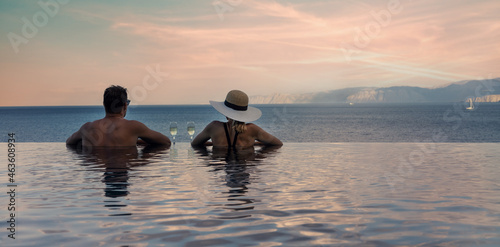 couple enjoying romantic view to the sea and drinking champagne in infinity pool at luxury resort. banner copy space