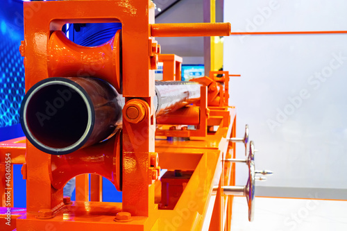 Wallpaper Mural Pipe production. Tube inside rolling machine. Equipment for testing and painting pipes. Pipeline manufacturing process. Black pipeline production. Orange vise with tube inside room. Torontodigital.ca