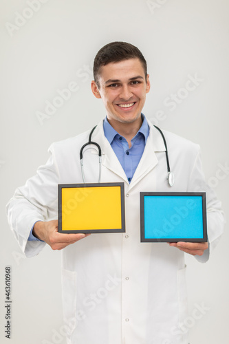 Mr. Doctor holds two picture frames or lettering in blue and yellow.