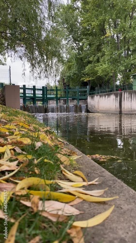 Dam on Porsuk river flowing through Kanlikavak park in Eskisehir Turkey in autumn with orange colored leaves on the ground photo