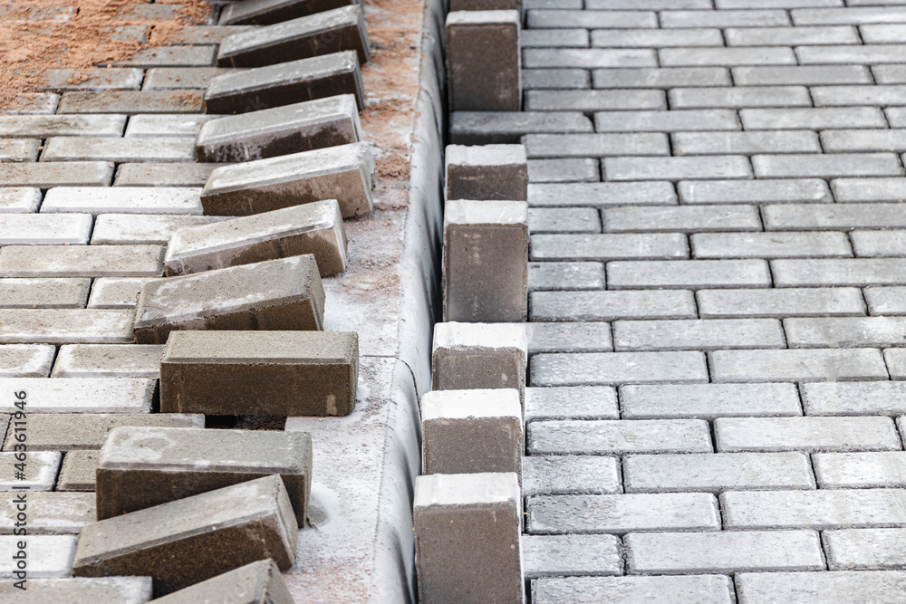 Pavement repairs and paving slabs laying on the prepared surface, with tile cubes in the background. Laying paving slabs in the pedestrian zone of the city. Paving slabs and curbs. Pavement repairs and paving slabs laying on the prepared surface, with tile cubes in the background. Laying paving slabs in the pedestrian zone of the city. Paving slabs and curbs.