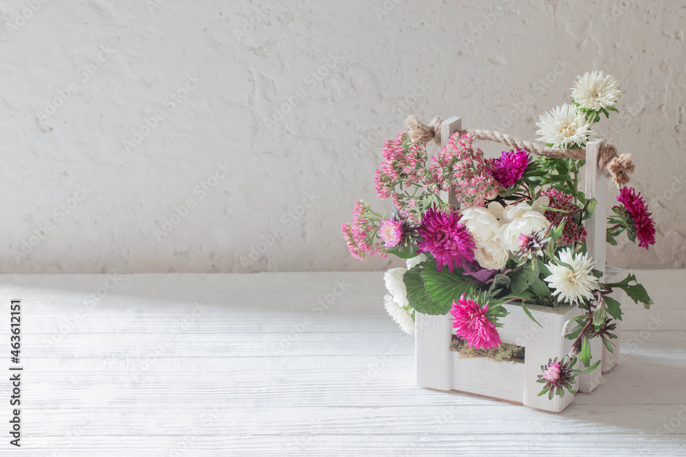 pink and white flowers in wooden basket on white background