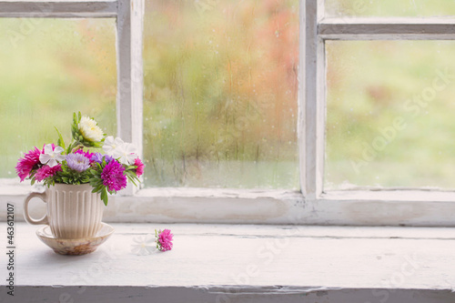 flowers in little cup on old white windowsill