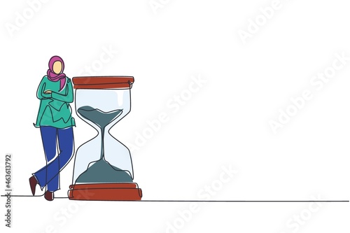 Single continuous line drawing happy Arab businesswoman lean on huge giant hourglass. Time is money financial investment. Time management conceptual metaphor. One line draw design vector illustration