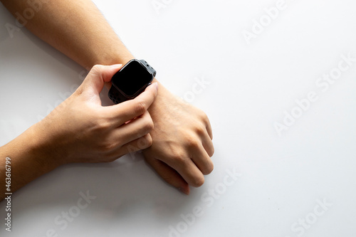 businessman wearing digital smart watch in hand touching screen to open notification, read message and activity tracker in wrist on white table background.