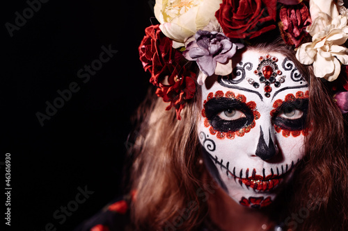 Fototapeta Naklejka Na Ścianę i Meble -  Woman in santa muerte makeup on a black background. Girl wearing traditional mexican holy death costume for halloween. Copy space