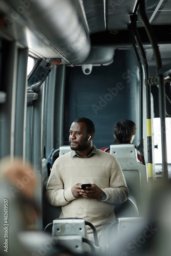 Vertical portrait of African-American man looking at window in bus while traveling by public transport in city