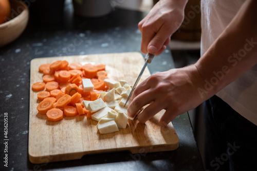 Mężczyzna krojący selera i marchewkę na desce do krojenia w kuchni