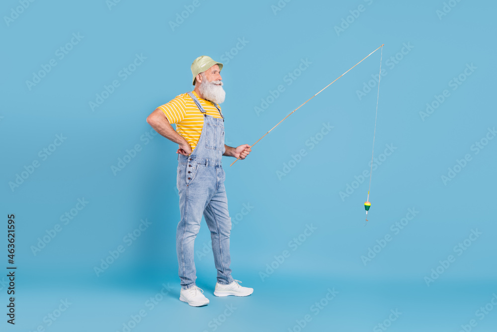 Full size profile side photo of aged man fishing hold spinning rod look empty space isolated over blue color background