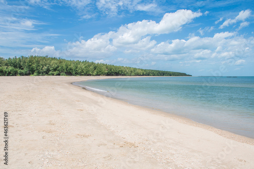 Beautiful bay, clean white sand beach With the blue sky, white clouds, quiet, green trees in the distance.