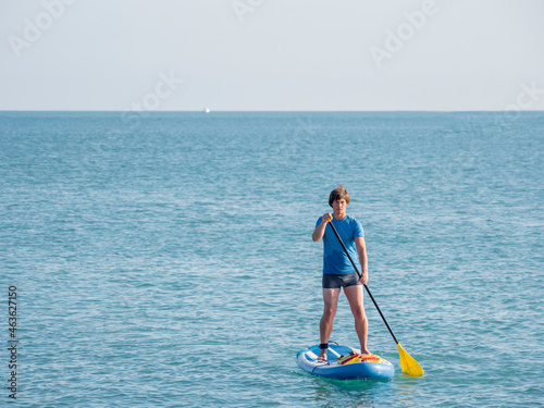 Paddle boarder. Sportsman paddling on stand up paddleboard. SUP surfing. Active lifestyle. Outdoor recreation. Vacation on seaside.
