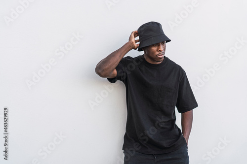 Chico negro atlético vestido completamente de negro sobre fondo claro con vaso de cafe