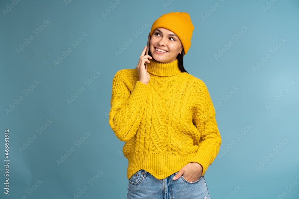 Waist up body size view of lovely focused cheerful girl wearing knitted sweater using gadget and having pleasure conversation isolated over vibrant blue color background Waist up body size view of lovely focused cheerful girl wearing knitted sweater using gadget and having pleasure conversation isolated over vibrant blue color background