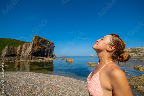 Happy woman in bikini breathing fresh air on the beach