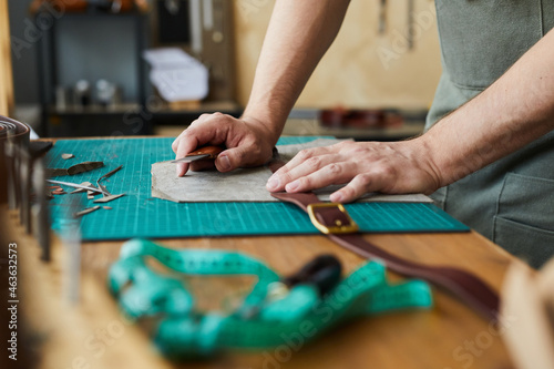 Side view closeup of unrecognizable male artisan making leather belt in tanners workshop, craftsmanship concept, copy space photo