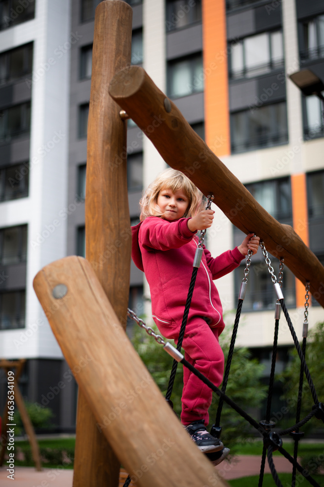 Little girl 5 years old blonde in red clothes plays on the playground, happy childhood Little girl 5 years old blonde in red clothes plays on the playground, happy childhood