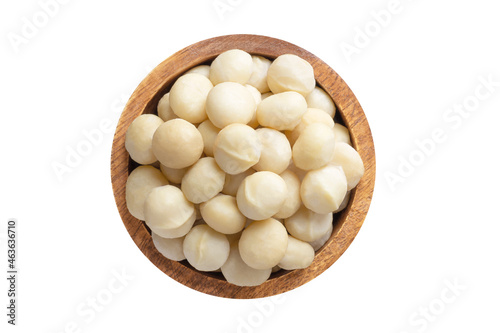 macadamia nuts peeled in wooden bowl isolated on white background. Vegan food, top view. photo