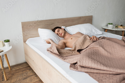 shirtless transgender man sleeping in bed at home
