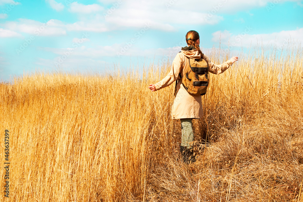 Warm autumn portrait of a girl outdoors. Unrecognizable woman traveler with backpack enjoying the view. Warm autumn portrait of a girl outdoors. Unrecognizable woman traveler with backpack enjoying the view.