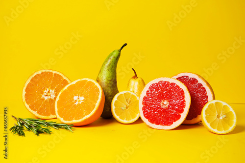 Tropical fruits grapefruit  orange  lime and pears on a yellow background with rosemary sprigs. ideal for advertising healthy food  a blog about vitamins and a healthy lifestyle. copy space