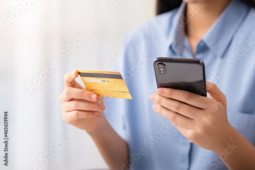 Woman using smartphone and credit card at home for shopping online.