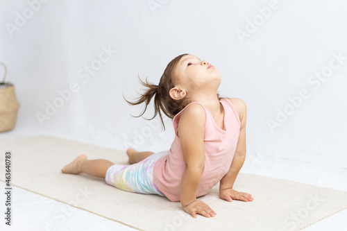 Little sporty girl practicing yoga, doing Ardha bhudjangasana exercise. Baby Cobra pose.