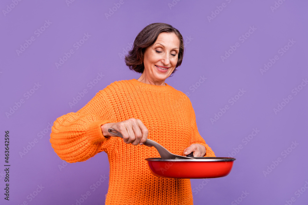 Profile side photo of attractive senior woman cook meal grill pan dinner isolated over purple color background Profile side photo of attractive senior woman cook meal grill pan dinner isolated over purple color background