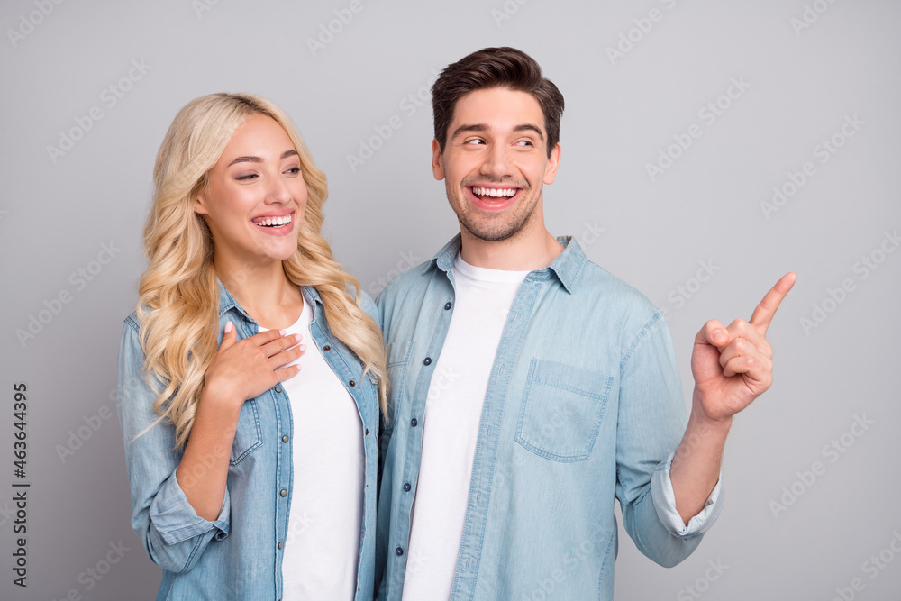 Photo of young couple happy positive smile indicate finger advertise direct decision isolated over grey color background Photo of young couple happy positive smile indicate finger advertise direct decision isolated over grey color background